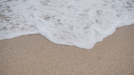 Beach waves foaming on white sand