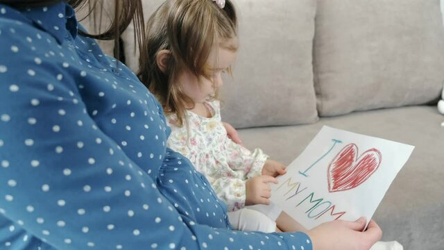 Little girl with pregnant mother drawing a picture at home