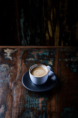 Cup of coffee on dark wooden background.