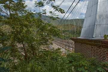 Fototapeta na wymiar Entrance point to the bridge of occidente antioquia colombia between forest overlooking the rio Cafe Claro agitated fast with green mountains