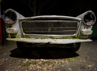 Night shot of the front mask of an abandoned decaying retro oldtimer french car