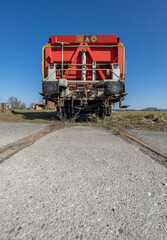 The last wagon of a standing train composition on a track in the middle of a meadow