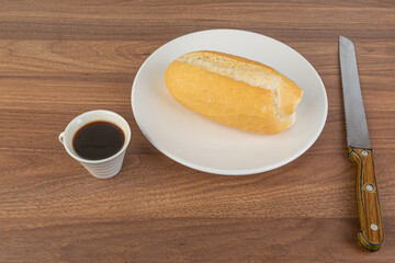 Brazilian Wheat Baked French Bread and coffee, on wooden table - perspective view.