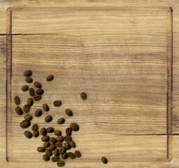 Top view of the old cracked and scratched wooden board with scattered roasted coffee beans. Vintage style background with copy space.