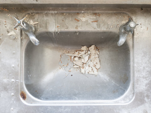 Top down view of a neglected, dirty stainless steel sink