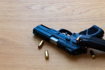 firearm, a pistol with a pistol magazine and ammunition on top of the wooden surface.