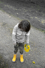 sad girl in yellow boots holds yellow flowers