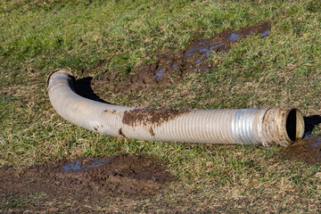 Big tube with slurry or manure is laying in the grass