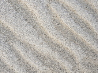 Fototapeta na wymiar Diagonal waves of sand. Sandy texture natural background