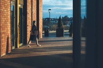 Young business lady is walking outside with a laptop after finishing a working day