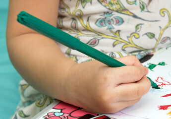 A girl hold green magic pen on right hand.