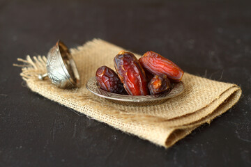 Dried palm date fruits in a silver bowl on black background