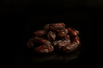 Dates on a black background. Dried fruits. Dried dates lie next to each other	
