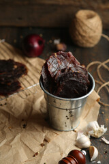 Homemade beef jerky seasoned with garlic, onion, pepper and salt. Jerky in a bucket on a wooden background