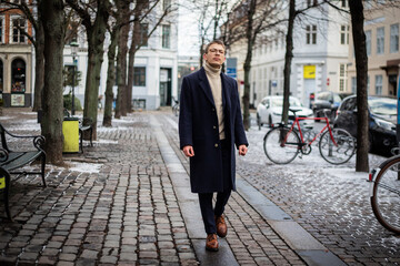 Stylish and elegant boy walks through the city center on a winter day