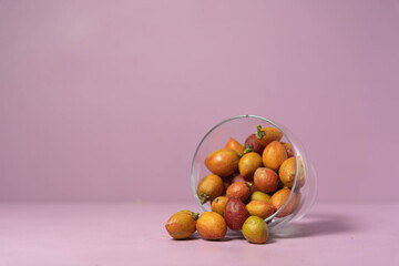 Caferana fruits (Bunchosia armeniaca) in natura served in a bowl on a pink background.