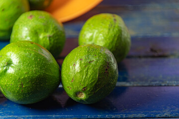 Natural avocado fruits (Persea americana) on blue wooden surface