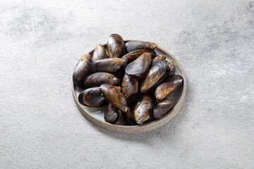 Shellfish raw Mussels on gray plate, gray background. Shellfish seafood. Top view.