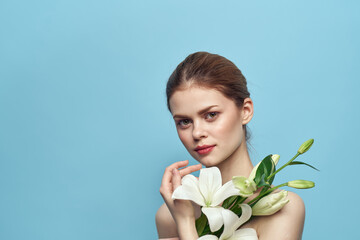 Woman with white flower on blue background cropped view of naked shoulders