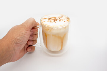 Hand holding hot  coffee with milky foam sprinkle with cocoa power for decoration in double wall glass isolated on white