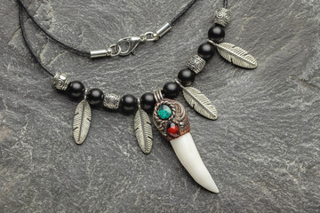 Pendant-amulet made of natural mineral balls with a crocodile fang. Stone background, close-up,...