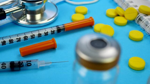 Heap of pills, syringe for insection, stethoscope and vaccine vial on blue background. Health care, doctor, clinic or hospital concept. Medical equipment