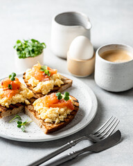 Scrambled egg sandwich with salmon on a ceramic plate on a white background, selective focus
