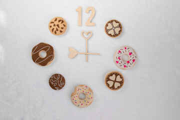 A clock made from a set of soft bagels and cookies are on a light soft textile . It is nine o'clock. The concept of time for children's games, needlework.