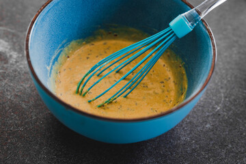 vegan batter mix for savoury muffins with olives and nutritional yeast in bowl with whisk, healthy plant-based food