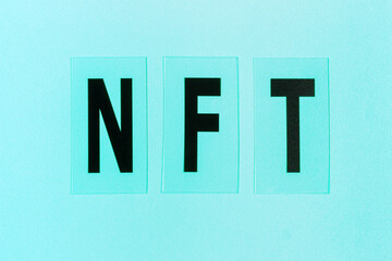 NFT inscription on blue background close-up view from above.