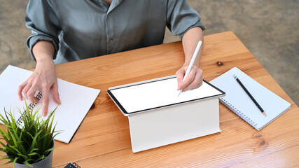 Businesswoman using digital tablet searching information at office desk.