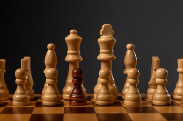 One black pawn unique and different in group of other chess pieces. Concept of diversity and...