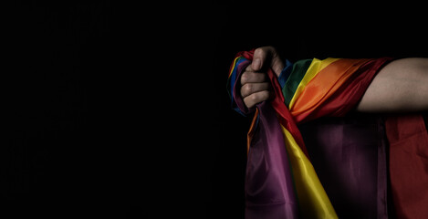 Flag of pride. LGBTQ flag and hand. Lesbian Gay Bi sexsual Transgender Queer or homosexsual pride Rainbow flag. black background. Represent hand symbol of freedom equality.