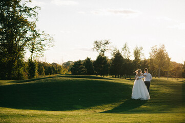 Happy husband and wife. Wedding day. Beautiful nature. Walk during the photo session. They smile at each other. Holding hands.