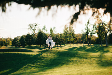 Happy husband and wife. Wedding day. Beautiful nature. Walk during the photo session. They smile at each other. Holding hands.
