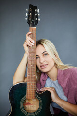 Happiness young woman play music with acoustic guitar on blue background. Portrait cheerful female...