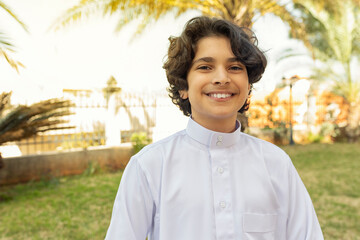 Arabian boy wearing traditional clothing smiling outdoors