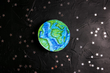 Drawn planet Earth among the stars on a black background. Science, ecology, environmental...
