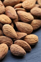 Almond nut. Raw almonds nuts heap on black slate background.Nuts and seeds  closeup. Healthy fats.