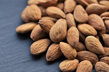 Almond nut. Raw almonds nuts heap on black slate background.Nuts and seeds  closeup.Tasty snack. Healthy fats.