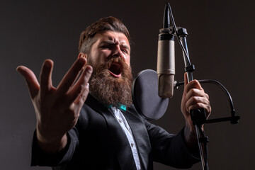 Classic singer in suit. Handsome man in recording studio. Music performance vocal. Singer singing song with a microphone.