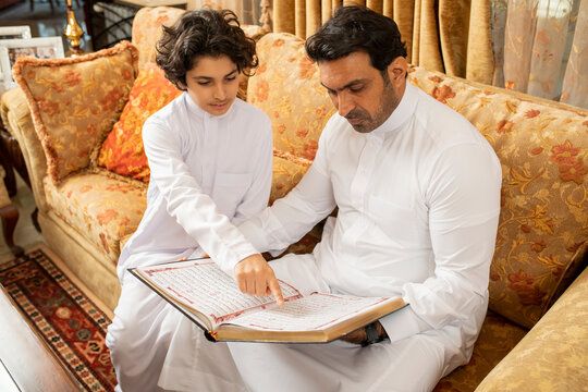 Arabian Father and Son reading Quran Holy Book