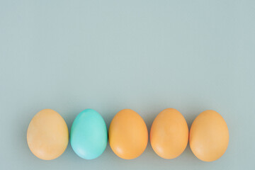Easter eggs are yellow except for one blue on a blue background. Creative Easter background. Copy space, top view, flat lay