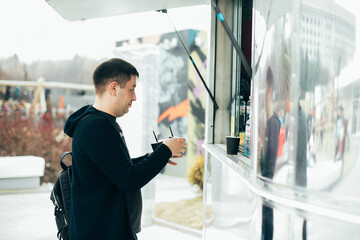 Street food concept. Man standing near a food track and waiting his order. Lifestile concept.