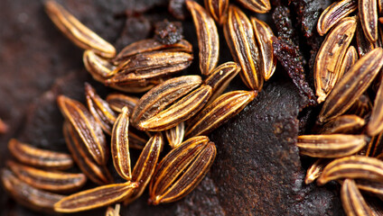 Cumin seeds on rye bread as background.