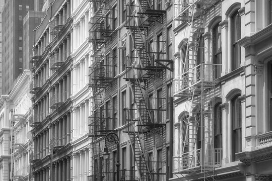 Row of old buildings with iron fire escapes, black and white picture, New York City, USA.