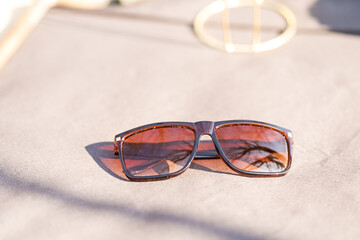 Fototapeta na wymiar Classic Sunglasses design for men and ladies with brown lenses and brown frame shoot outside in a summer day closeup. Selective focus. High quality photo