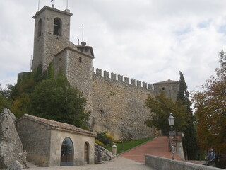 Fototapeta na wymiar San Marino, First Tower. Front of the castle surrounded by mighty stone walls, the bell tower and the entrance door that was a drawbridge
