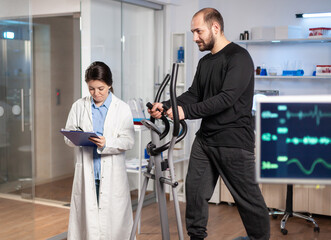 Sport researcher in laboratory taking notes while muscular athlete athlete is running, heart rate examination. Testing endurance in professional biomechanics lab.