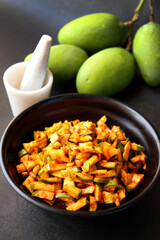 Green mango salad. Raw mango instant pickle. also known as kairichi koshimbir in Marathi. copy space over black background. Chopped raw green mangos mixed with salt, red chilli powder and sugar. 